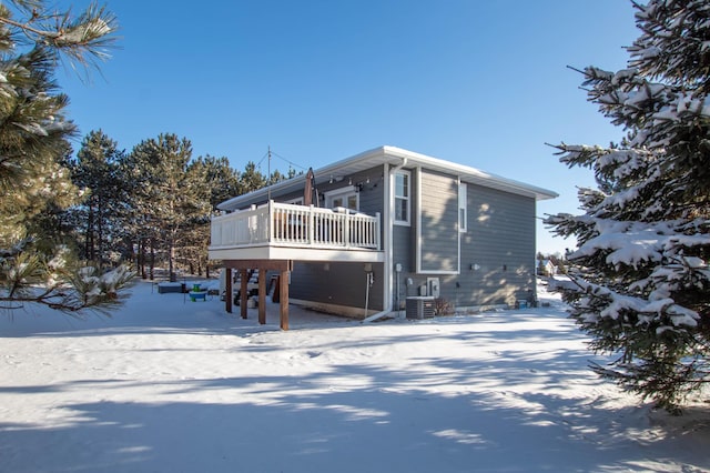 snow covered rear of property featuring central AC