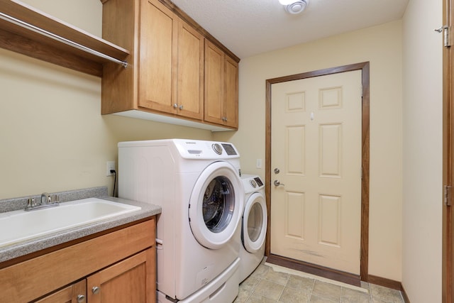 clothes washing area with cabinets, sink, washer and dryer, and a textured ceiling