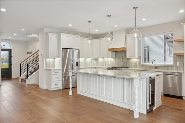 kitchen featuring white cabinetry, stainless steel appliances, a kitchen island, and custom range hood