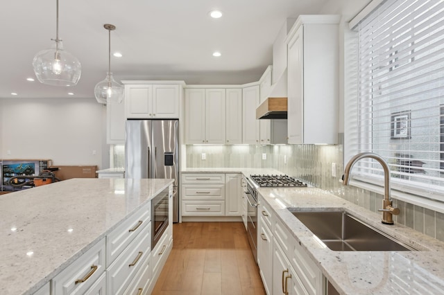 kitchen with white cabinets, light stone countertops, hanging light fixtures, and sink