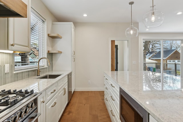 kitchen with hanging light fixtures, sink, light stone countertops, appliances with stainless steel finishes, and white cabinetry