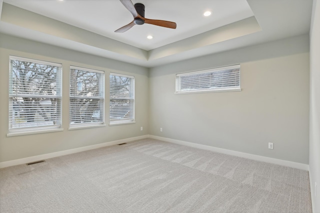 empty room with carpet, ceiling fan, and a tray ceiling