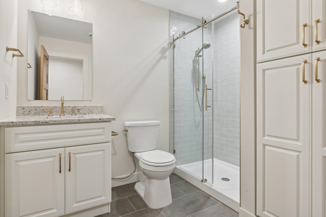 bathroom featuring tile patterned flooring, vanity, toilet, and a shower with door