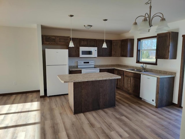 kitchen featuring white appliances, sink, decorative light fixtures, light hardwood / wood-style floors, and a kitchen island