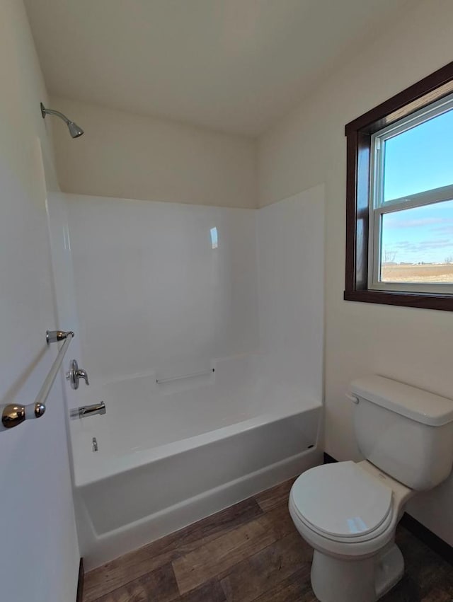 bathroom with hardwood / wood-style floors, shower / bathtub combination, and toilet