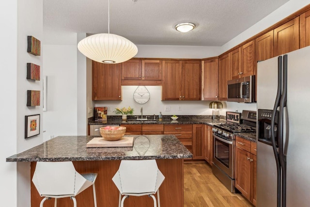 kitchen featuring a kitchen island, appliances with stainless steel finishes, decorative light fixtures, sink, and a breakfast bar area