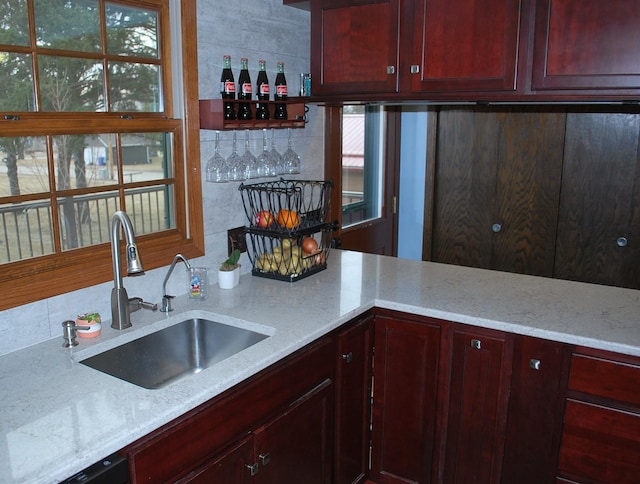 kitchen with light stone countertops, sink, and black dishwasher