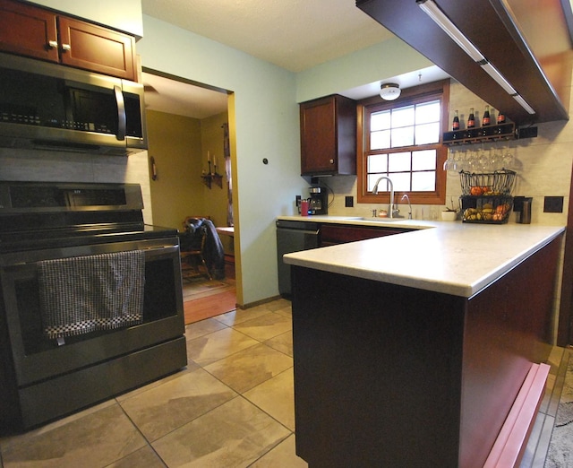 kitchen with kitchen peninsula, sink, light tile patterned flooring, and black appliances