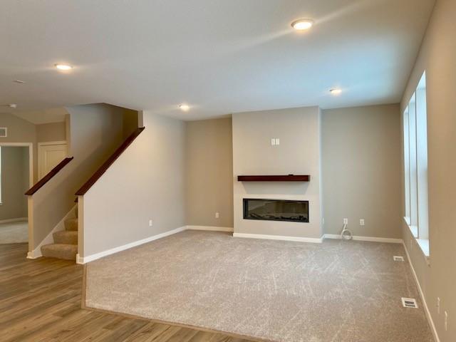 unfurnished living room featuring plenty of natural light and hardwood / wood-style floors