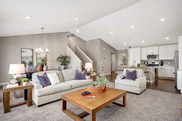 living room featuring vaulted ceiling, light colored carpet, and a chandelier