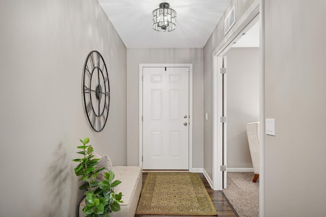 entryway featuring dark wood-type flooring and an inviting chandelier