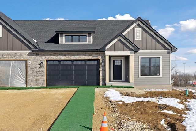 view of front of home with board and batten siding, a shingled roof, a garage, stone siding, and driveway