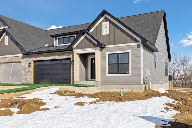 view of front of house featuring stone siding, roof with shingles, board and batten siding, and driveway