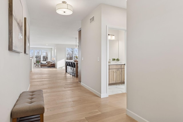 corridor featuring visible vents, baseboards, and light wood-type flooring