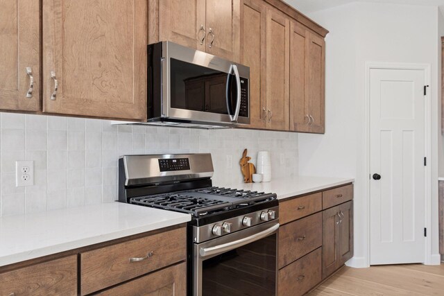 kitchen featuring brown cabinets, tasteful backsplash, appliances with stainless steel finishes, and light countertops