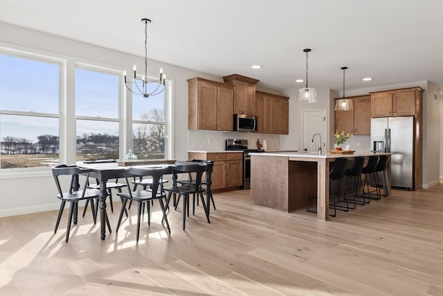 kitchen featuring stainless steel appliances, pendant lighting, and brown cabinetry