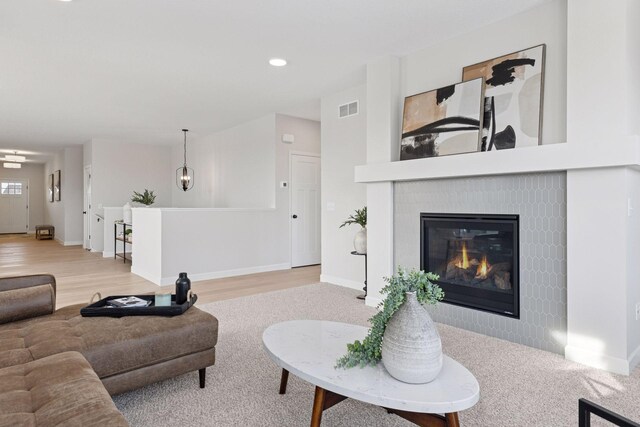 living area featuring a glass covered fireplace, baseboards, and visible vents