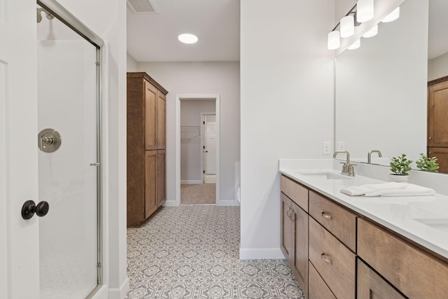 full bath with baseboards, double vanity, a sink, a shower stall, and a walk in closet