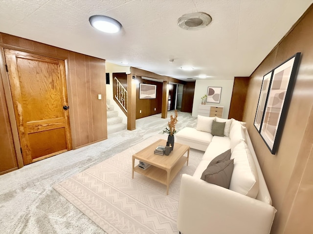 living room featuring light carpet, a textured ceiling, and wood walls