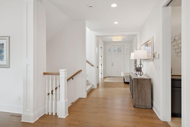 corridor with light wood-type flooring and an inviting chandelier