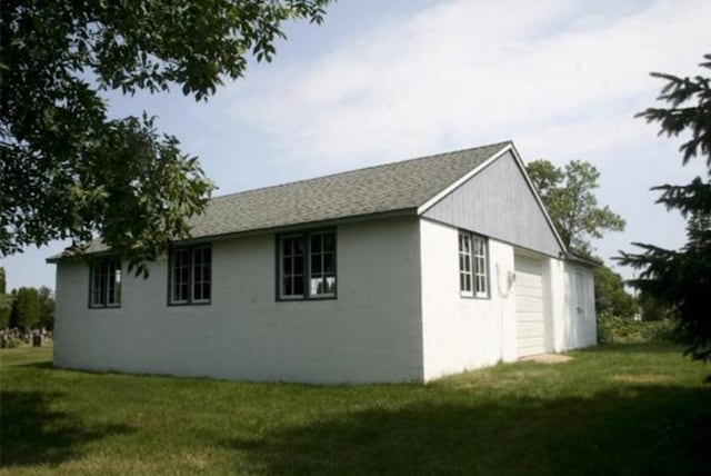 view of home's exterior with a garage, an outbuilding, and a yard