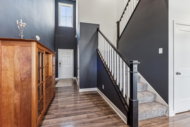 staircase with hardwood / wood-style flooring and a high ceiling