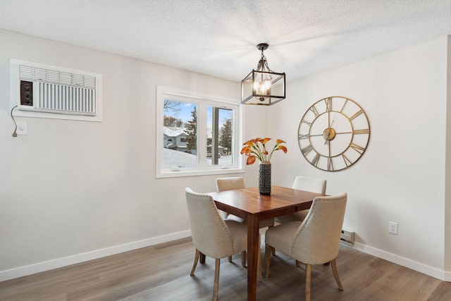 dining area featuring a wall mounted AC, an inviting chandelier, a textured ceiling, and hardwood / wood-style floors