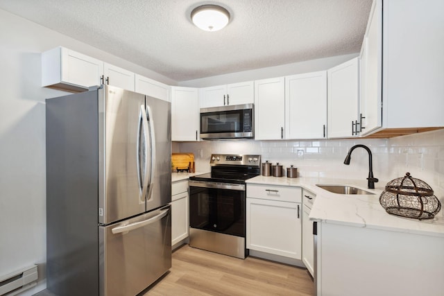 kitchen featuring a baseboard heating unit, appliances with stainless steel finishes, a textured ceiling, and white cabinetry