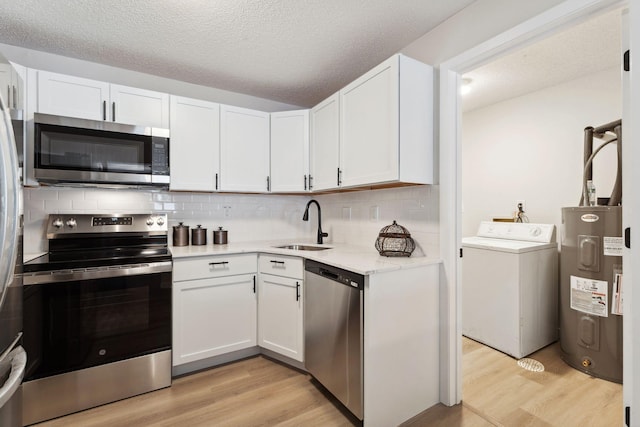 kitchen featuring washer / dryer, water heater, stainless steel appliances, and white cabinets