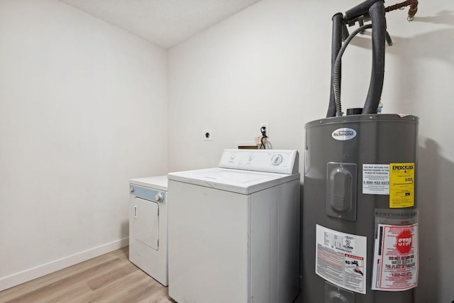 clothes washing area featuring washing machine and dryer, light hardwood / wood-style flooring, and water heater