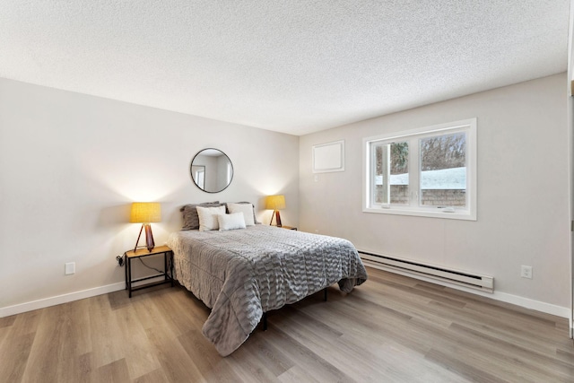 bedroom with light hardwood / wood-style floors, baseboard heating, and a textured ceiling