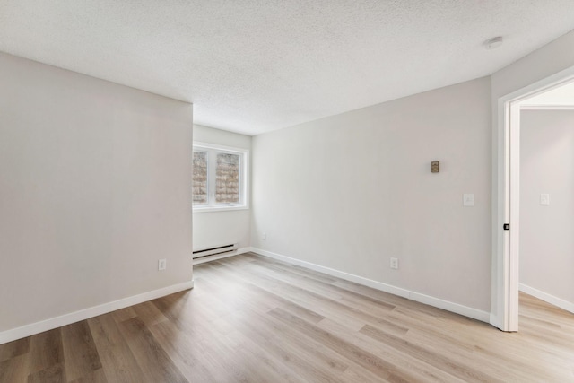 empty room with a baseboard radiator, a textured ceiling, and light hardwood / wood-style flooring