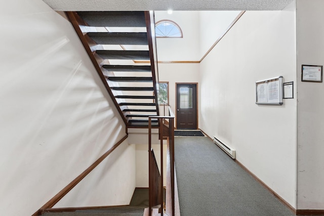 stairway with carpet floors, baseboard heating, and a high ceiling