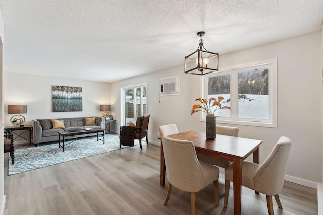 dining room featuring a chandelier, baseboards, a textured ceiling, and light wood finished floors