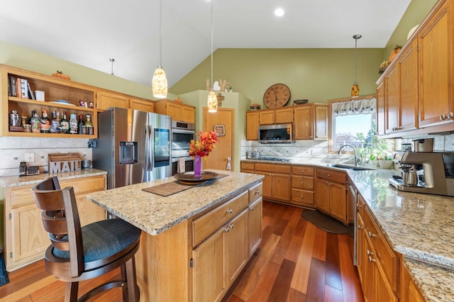 kitchen featuring sink, tasteful backsplash, a kitchen bar, a kitchen island, and appliances with stainless steel finishes