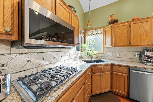 kitchen featuring hanging light fixtures, sink, vaulted ceiling, decorative backsplash, and appliances with stainless steel finishes