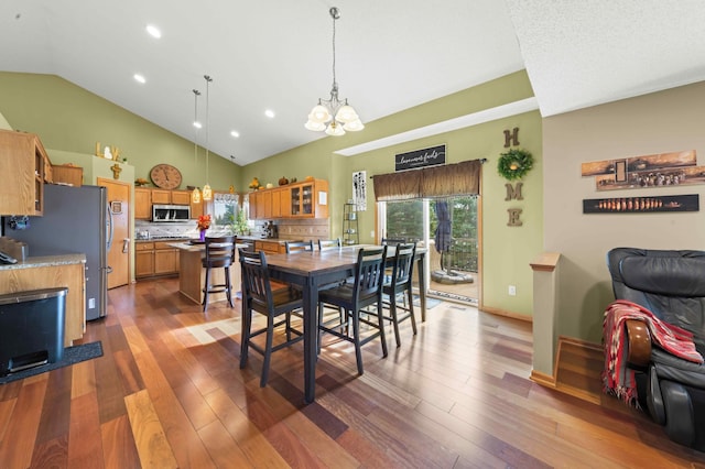 dining area with high vaulted ceiling, a chandelier, and dark hardwood / wood-style floors