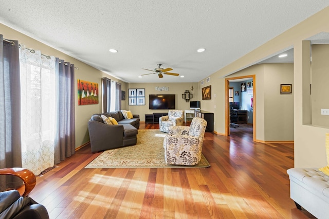 living room with a textured ceiling, hardwood / wood-style flooring, and ceiling fan