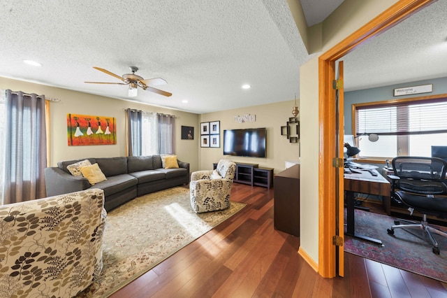 living room with a textured ceiling, ceiling fan, and dark wood-type flooring