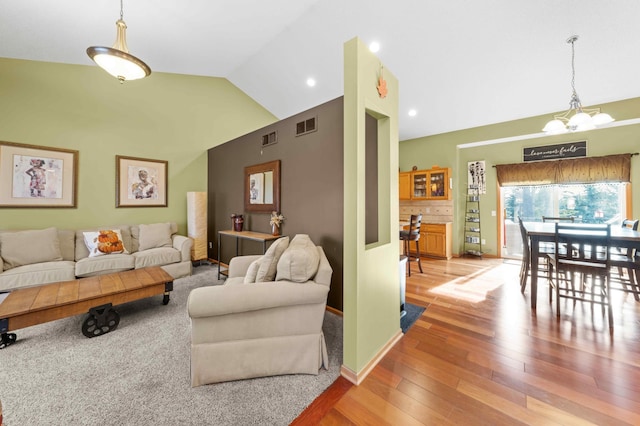 living room featuring a chandelier, wood-type flooring, and vaulted ceiling