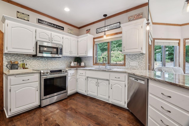 kitchen featuring appliances with stainless steel finishes, dark wood-type flooring, sink, pendant lighting, and white cabinets