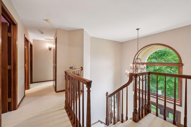 hall with a chandelier and light colored carpet