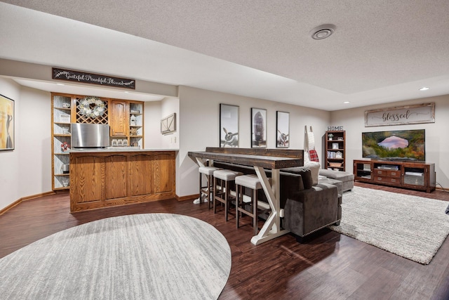 living room with bar area, dark wood-type flooring, and a textured ceiling