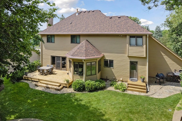 rear view of property featuring a sunroom, a yard, and a deck