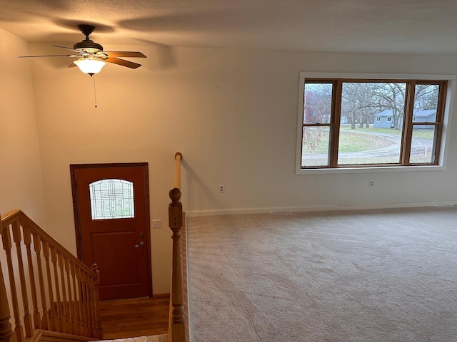 entrance foyer with ceiling fan and carpet floors