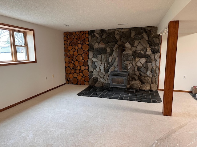 unfurnished living room featuring a wood stove, a textured ceiling, and dark carpet