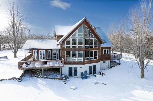 snow covered rear of property with a wooden deck