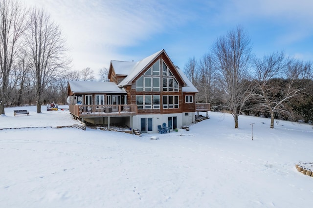 snow covered back of property with a wooden deck