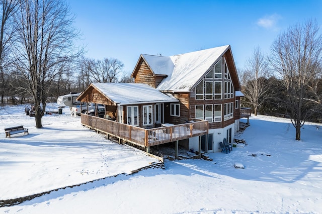 snow covered back of property with a deck