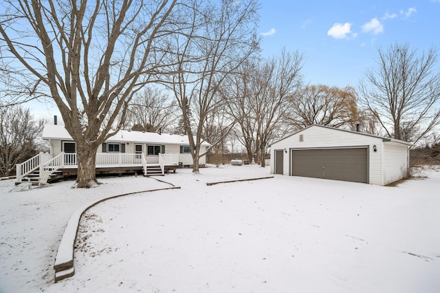 snowy yard featuring covered porch, a garage, and an outdoor structure